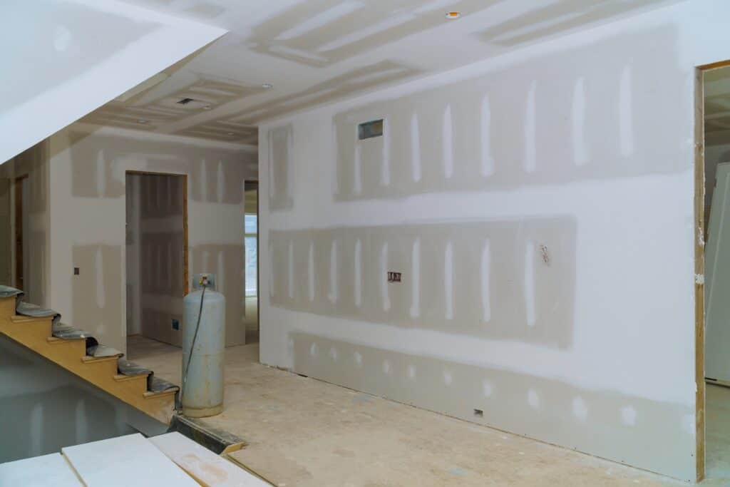 Interior drywall installation with unfinished walls and ceiling in a residential space.