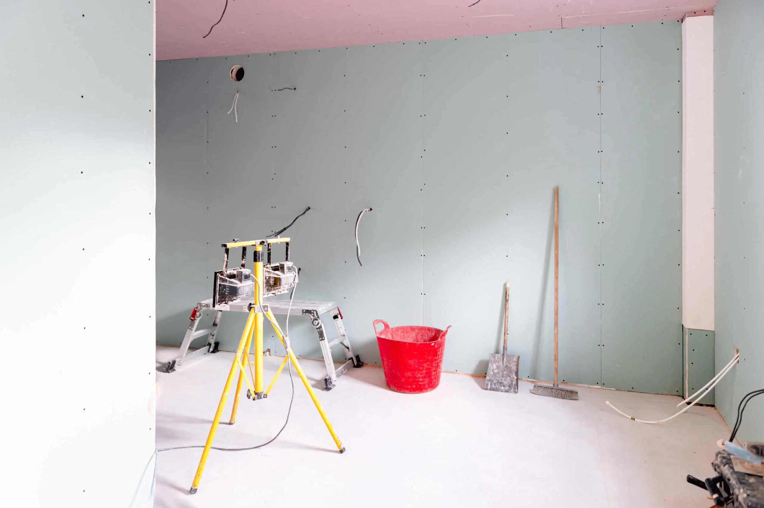 Drywall installation with tools and materials in a construction site.