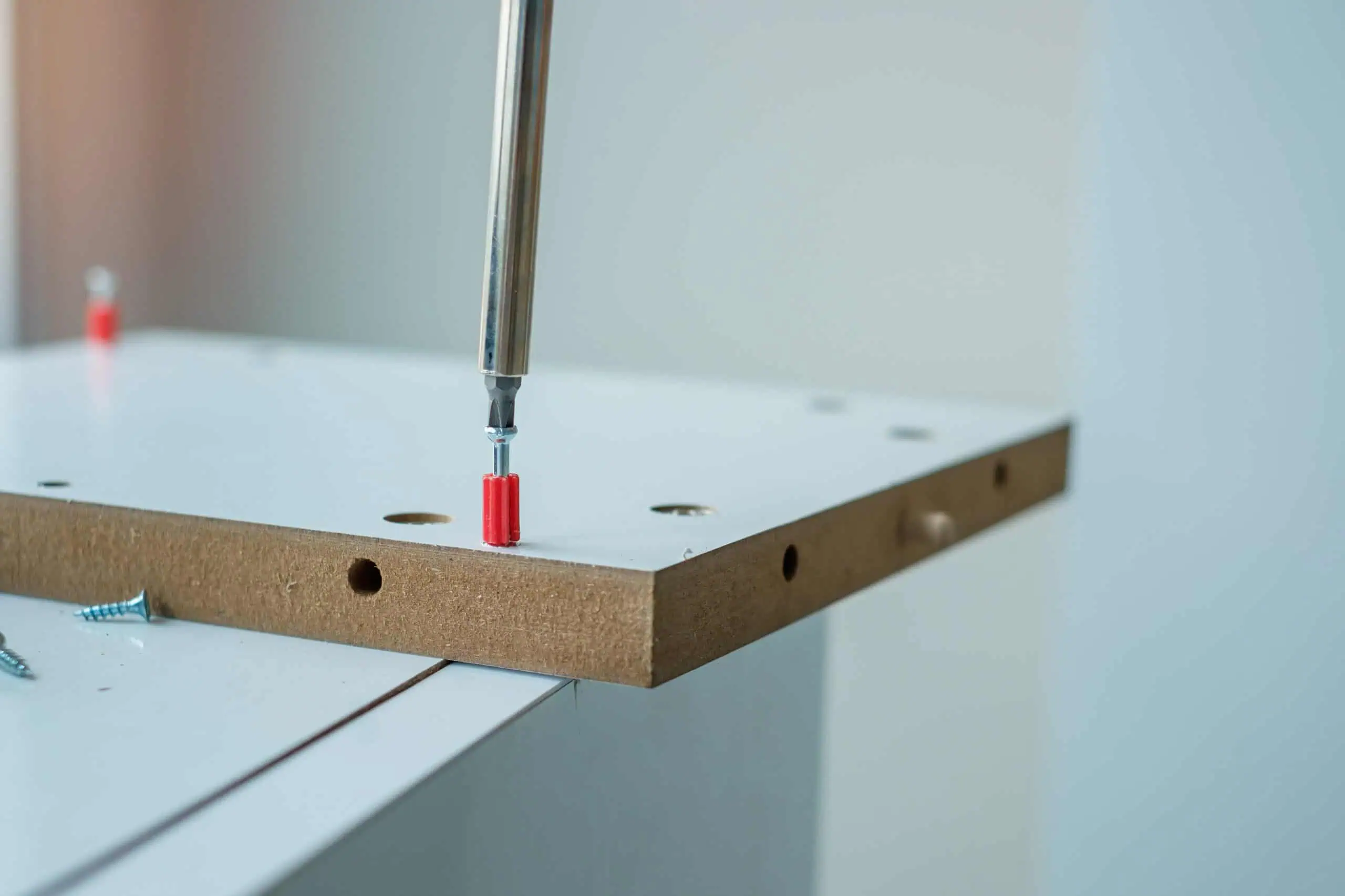 Drywall installation with screwdriver on a wooden board, close-up of tools and materials used in dry.