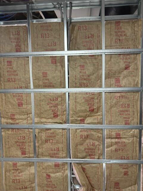 Fire-resistant insulation being installed behind drywall framing for enhanced safety.