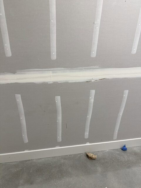 Interior drywall wall with joint tape and mud for smooth finish.