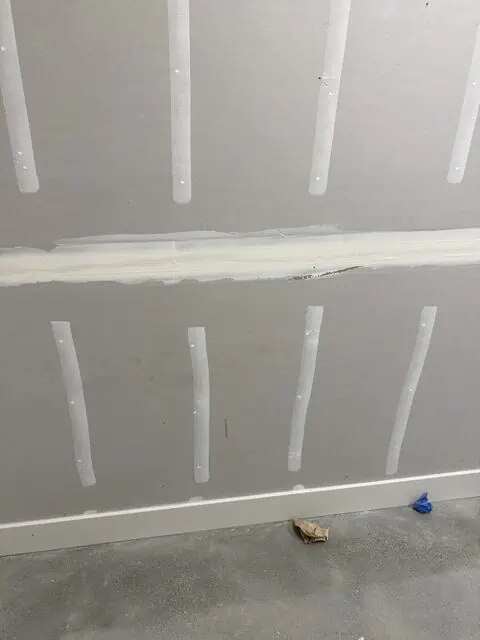 Interior drywall wall with joint tape and mud for smooth finish.