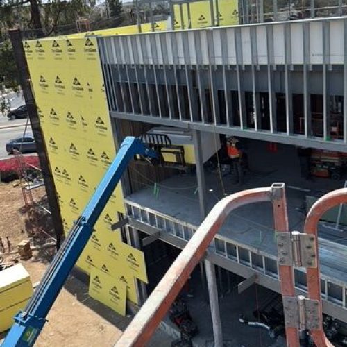 Construction site with steel framework and yellow insulation panels.