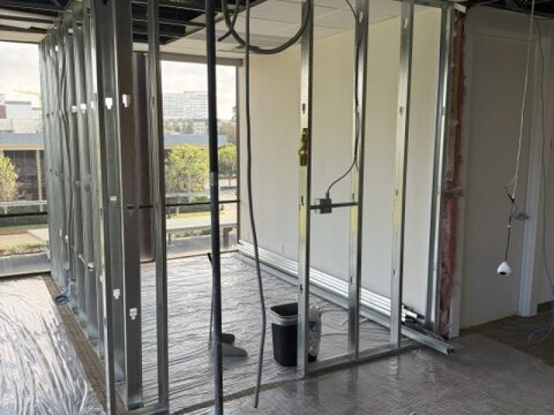 Drywall framing and electrical wiring installation at a construction site.